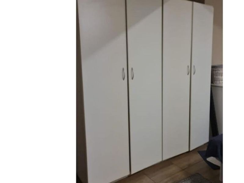A bedroom featuring a large, white built-in wardrobe with modern handles, providing ample storage space.