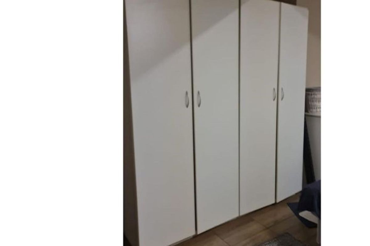 A bedroom featuring a large, white built-in wardrobe with modern handles, providing ample storage space.