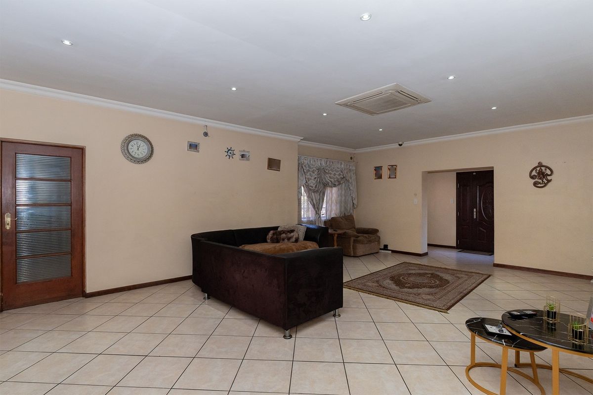 Spacious living room featuring neutral tiled flooring, recessed ceiling lighting, and a built-in ceiling air conditioning unit.