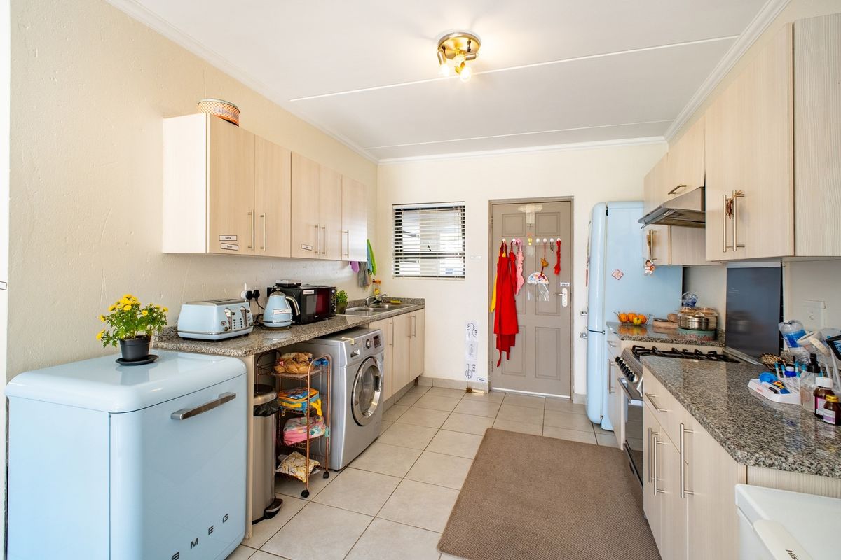 Functional kitchen featuring light wood cabinetry, granite countertops, integrated stove with extractor fan, and dedicated space for laundry appliances.