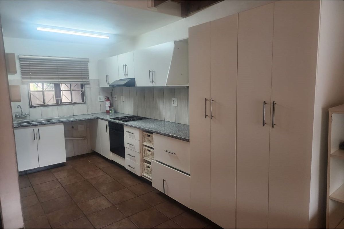A functional kitchen featuring white cabinetry, granite countertops, a built-in oven and hob, and tiled flooring.