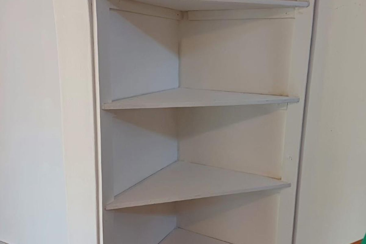 A built-in corner shelving unit featuring multiple tiers, integrated into an arched wall structure.