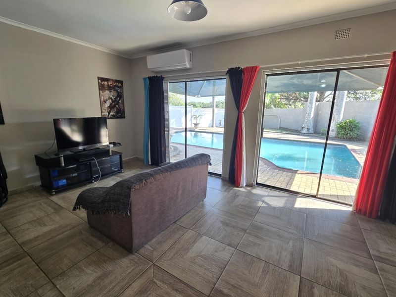 Spacious living room featuring tiled flooring and large sliding glass doors providing direct access to the outdoor pool area.