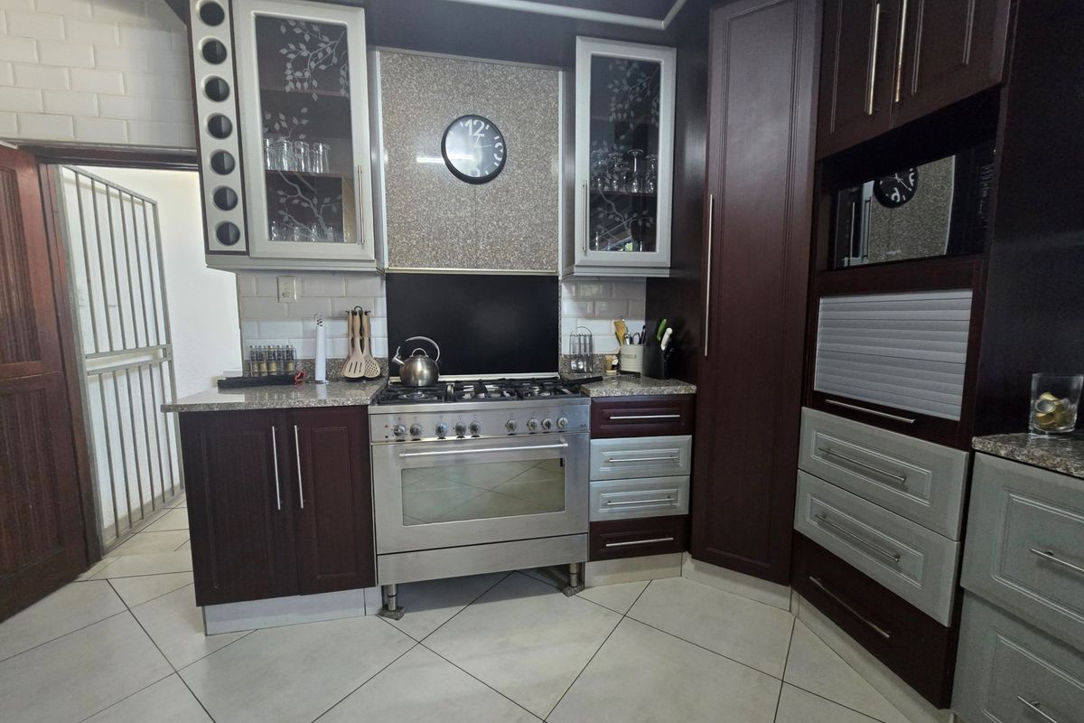 A well-appointed kitchen featuring dark wood cabinetry, granite countertops, a gas stove with oven, and a stylish subway tile backsplash.