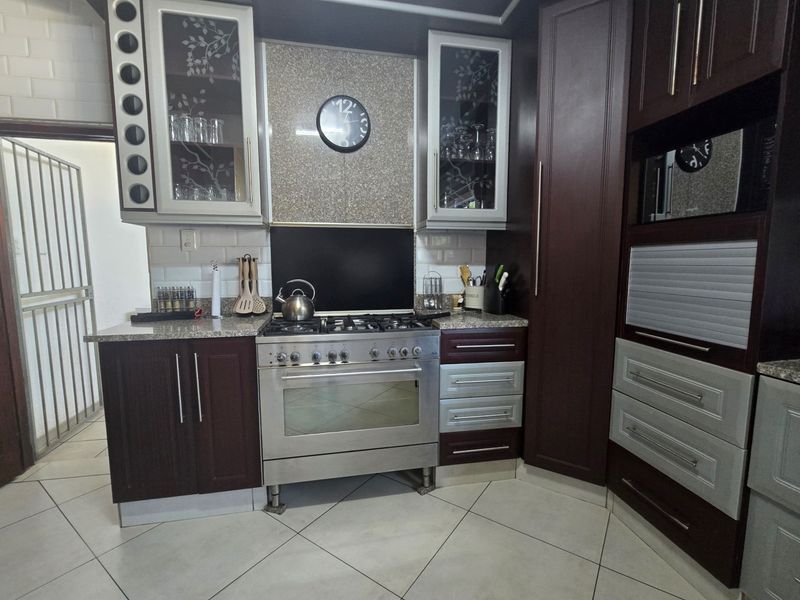 A well-appointed kitchen featuring dark wood cabinetry, granite countertops, a gas stove with oven, and a stylish subway tile backsplash.
