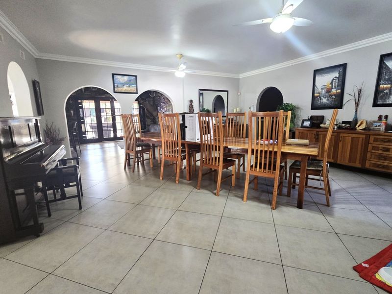 Spacious dining area featuring large format floor tiles, decorative archways, and ceiling fans, providing a bright and open space for family gatherings.