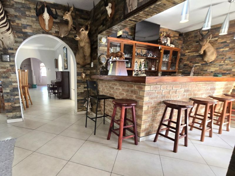 A rustic-style home bar featuring a brick base, stone-clad walls, and built-in cabinetry, creating a distinct entertainment space.