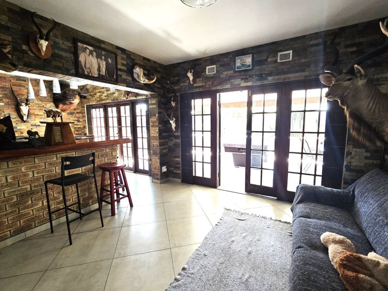 A dedicated bar area featuring stone-clad walls, a built-in brick bar counter, and large french doors providing access to the outdoor patio.