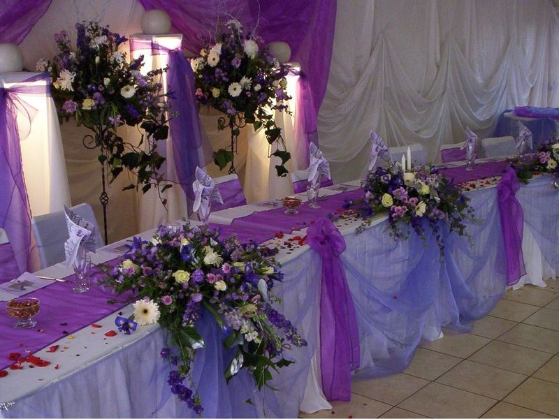 A decorated event space featuring draped fabric and floral arrangements set up for a formal gathering or wedding reception.