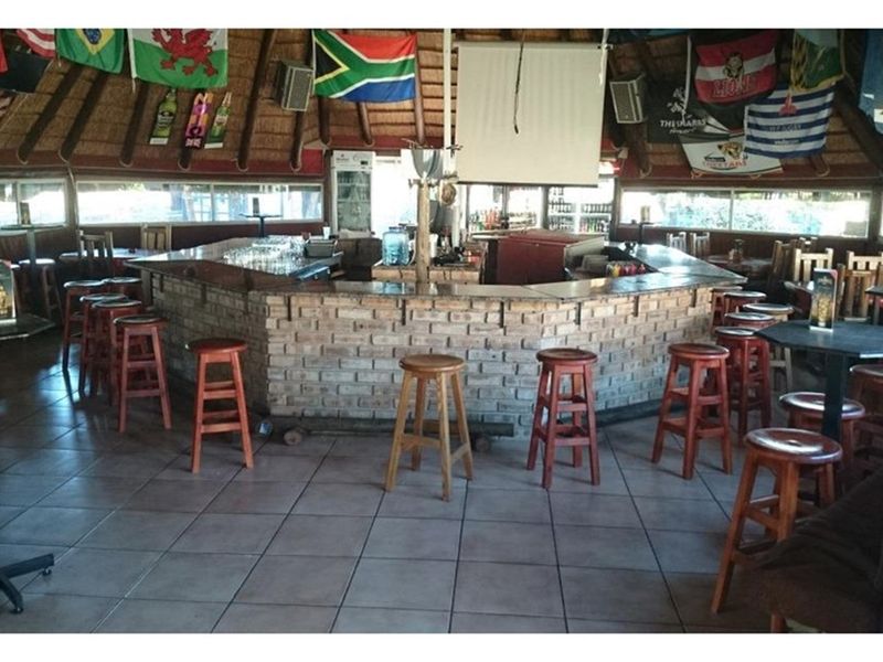 A rustic lodge bar area featuring a brick-faced counter, traditional thatched roof, and tiled flooring, providing a classic social space for guests.
