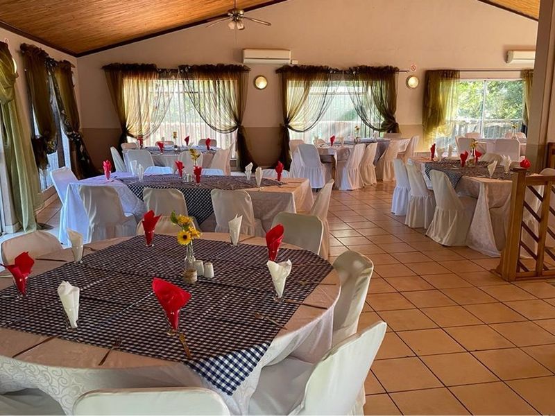 Spacious dining hall featuring a vaulted timber ceiling, ceramic tiled flooring, and multiple sliding glass doors providing natural light and access to the exterior.