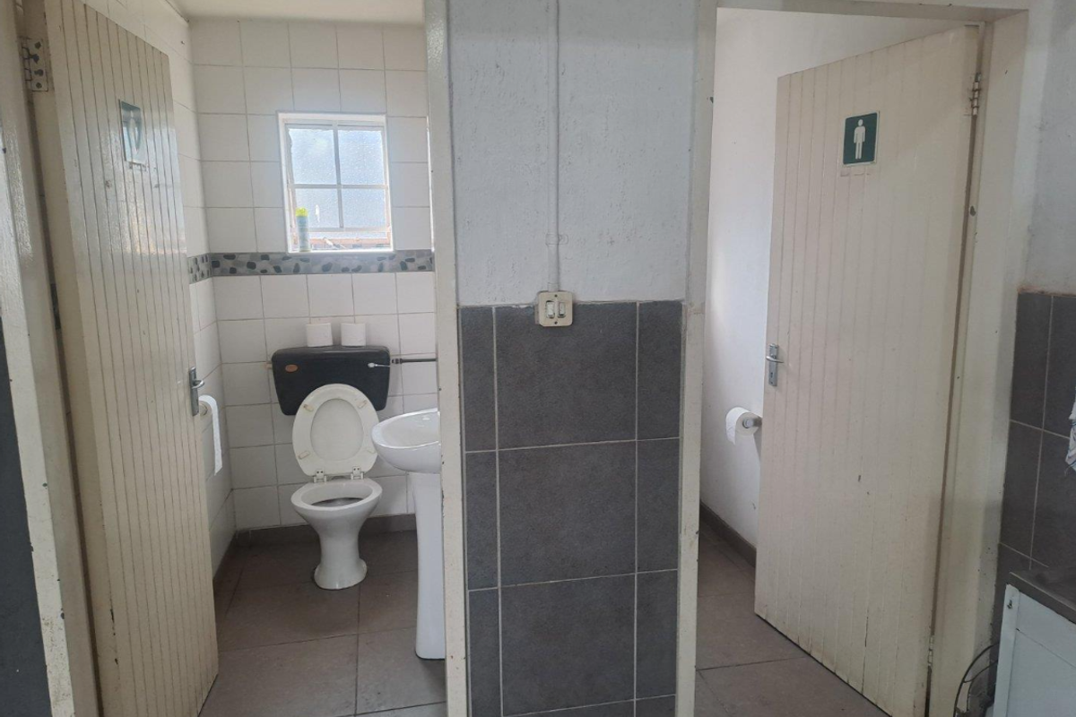 Functional industrial restroom facility featuring separate cubicles with pedestal basins and tiled wall finishes.