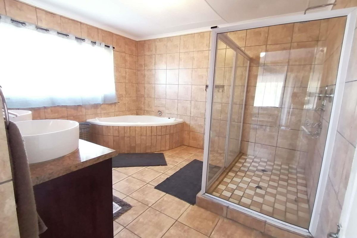 Spacious bathroom featuring a corner bathtub, a separate glass-enclosed shower, and tiled finishes throughout.