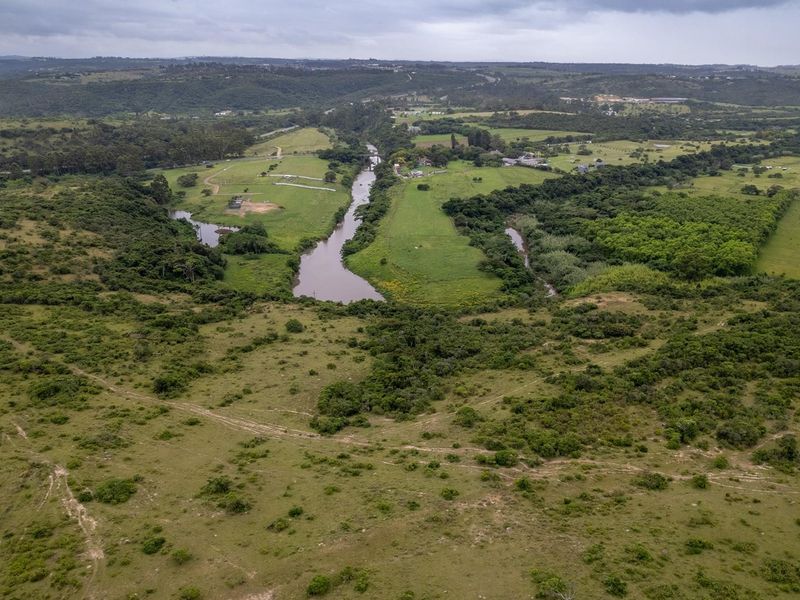 An expansive aerial view of the vacant residential land featuring natural vegetation, open grassland, and scenic river frontage.