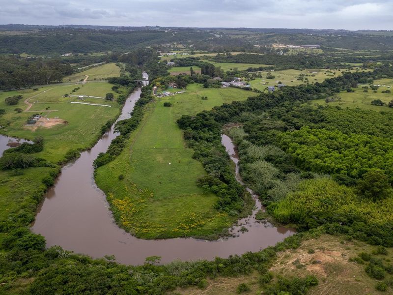 An aerial view of a large residential vacant land plot featuring extensive river frontage and natural landscape surroundings.