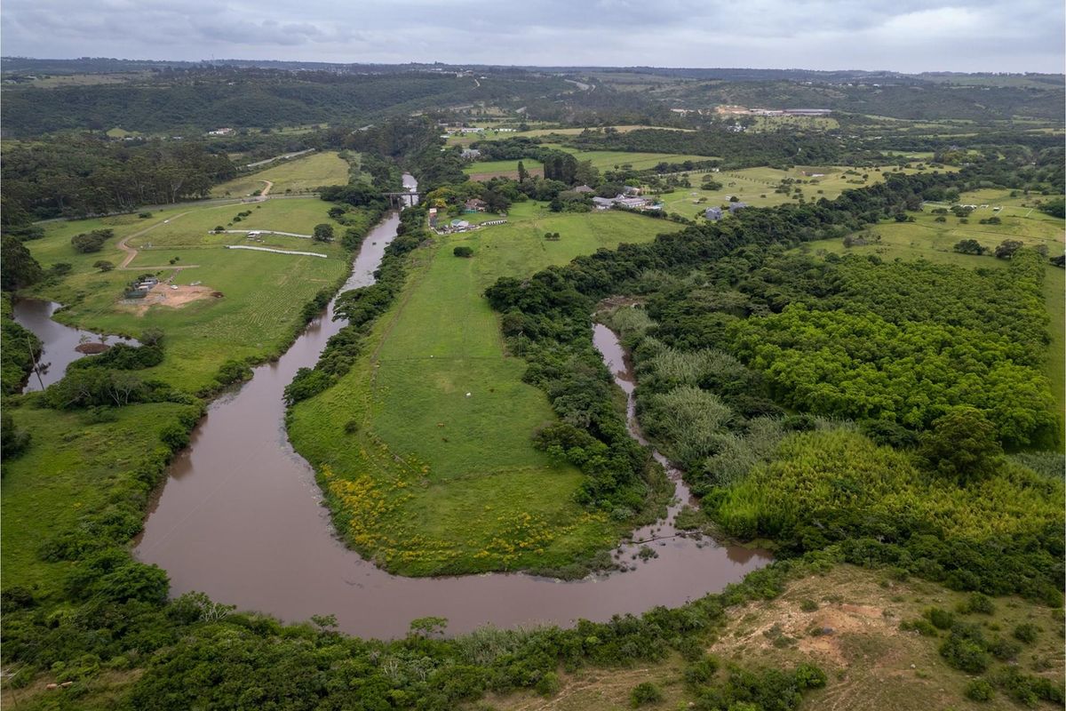 An aerial view of a large residential vacant land plot featuring extensive river frontage and natural landscape surroundings.