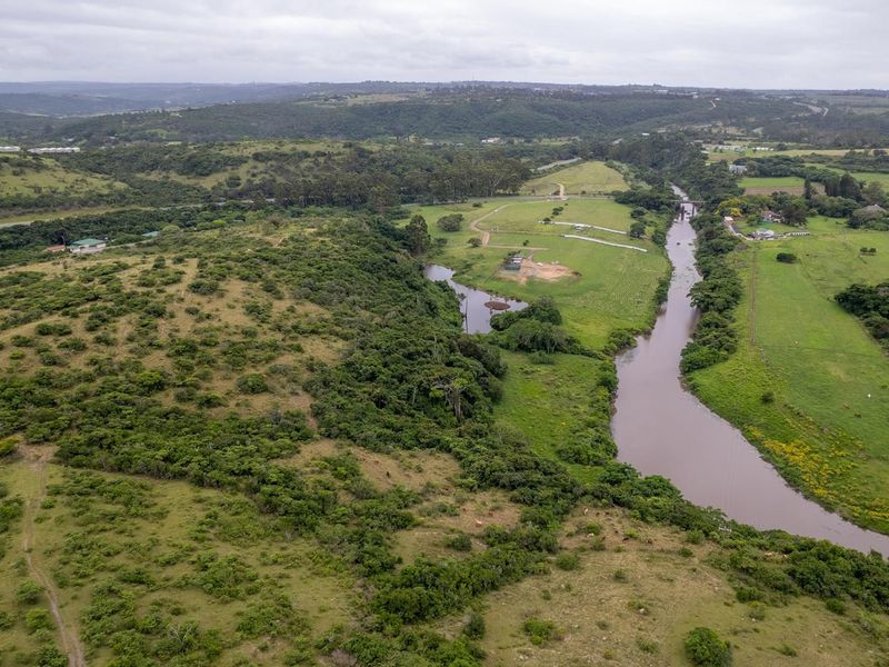 An aerial view of the vacant land featuring natural vegetation, open pasture, and a river running through the property.