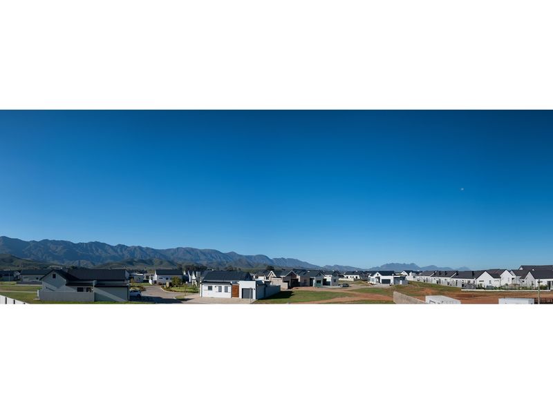 A panoramic aerial view of a modern residential estate featuring contemporary homes set against a scenic mountain range backdrop.