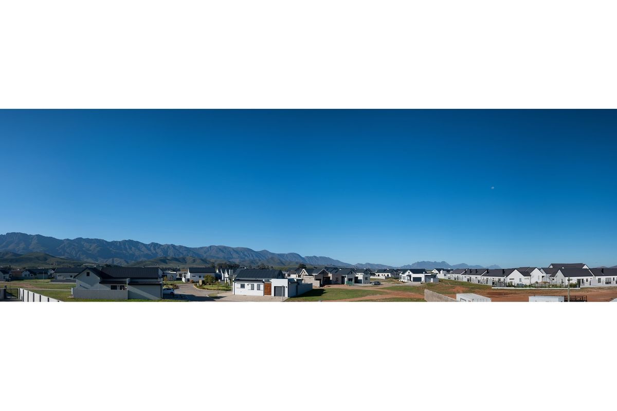 A panoramic aerial view of a modern residential estate featuring contemporary homes set against a scenic mountain range backdrop.