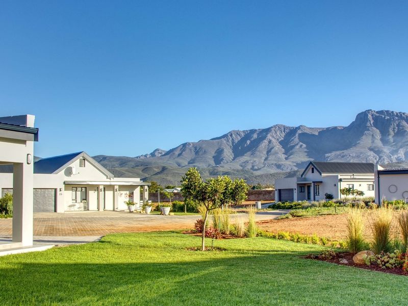 A well-maintained residential property exterior featuring a paved driveway, landscaped garden, and modern architectural design with scenic mountain views.