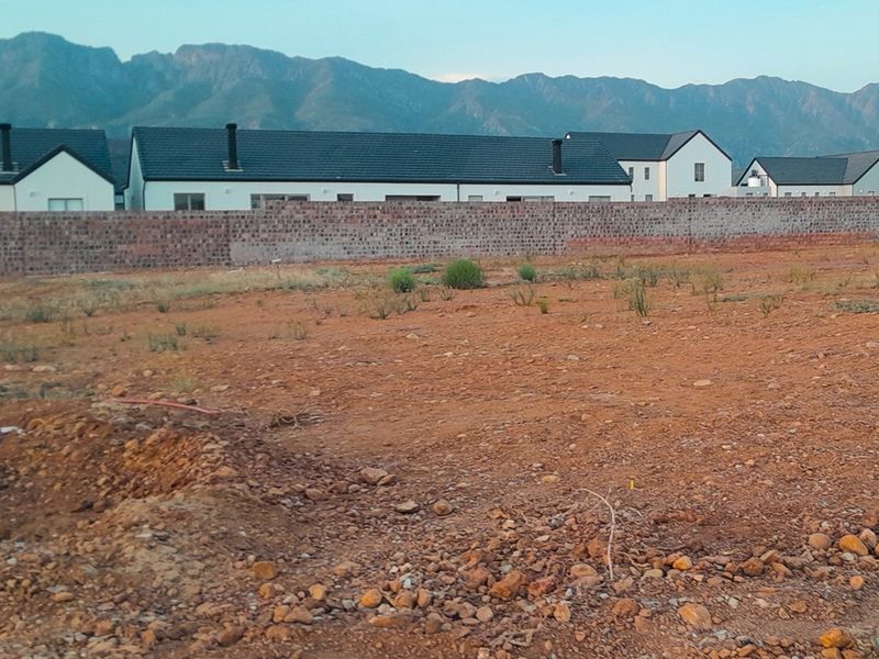 A vacant residential plot featuring a boundary wall and scenic mountain views, ready for development in a residential estate.