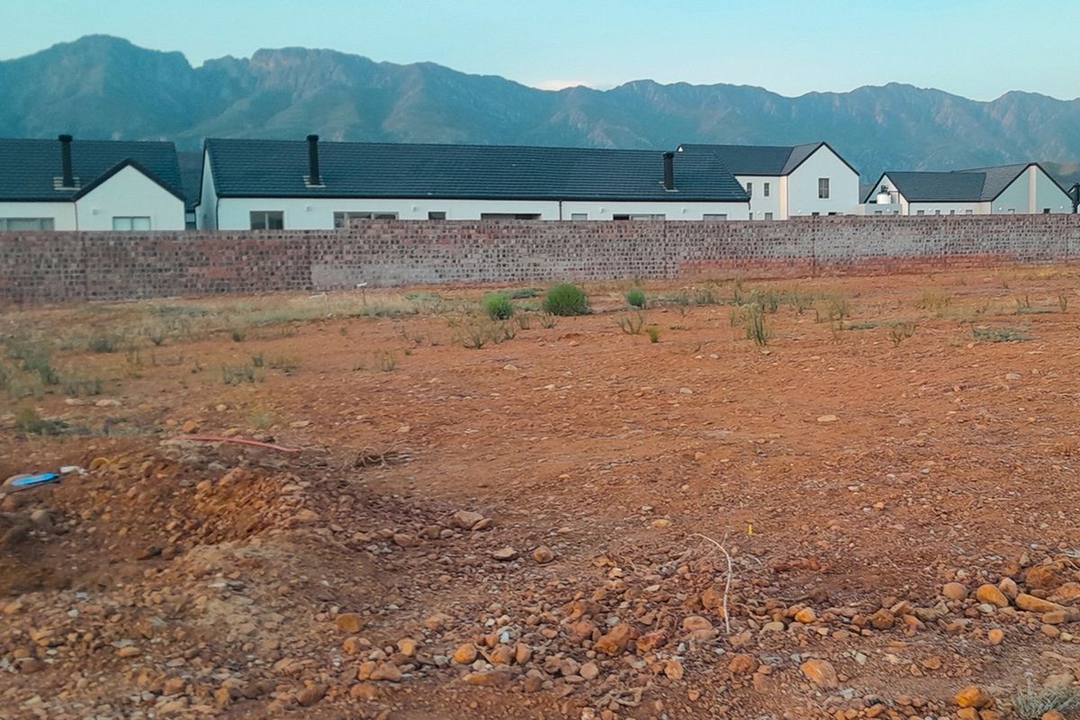 A vacant residential plot featuring a boundary wall and scenic mountain views, ready for development in a residential estate.