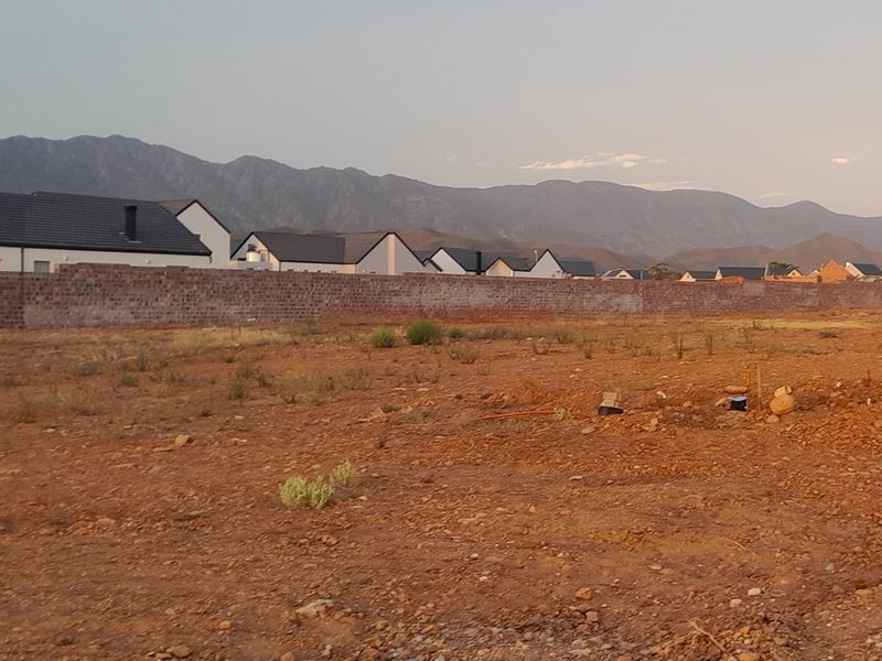 A vacant residential plot featuring a boundary wall and scenic mountain views, offering a blank canvas for new construction.