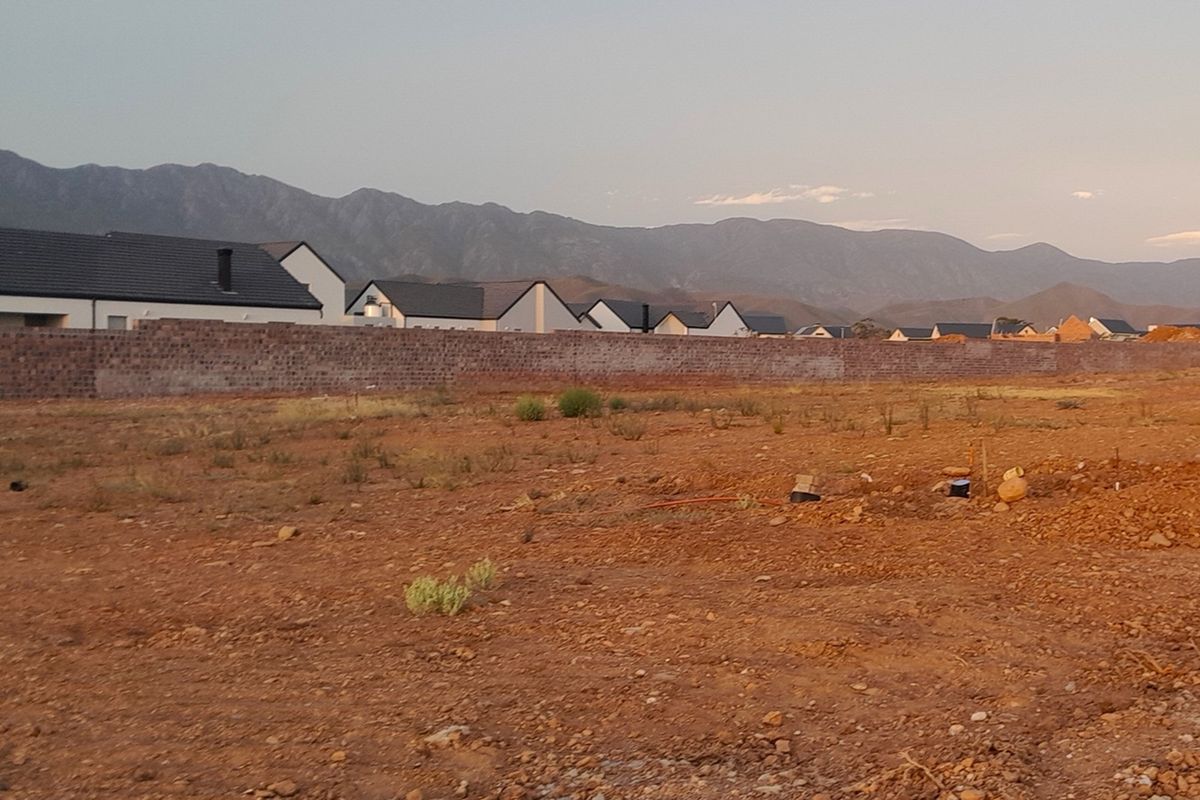 A vacant residential plot featuring a boundary wall and scenic mountain views, offering a blank canvas for new construction.