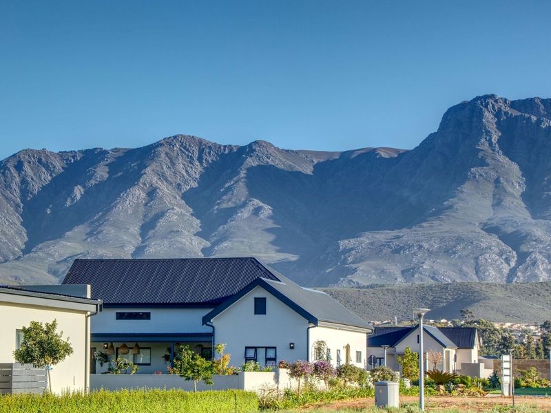A scenic view of residential properties set against a dramatic mountain range backdrop, showcasing the estate's natural surroundings and well-maintained landscape.