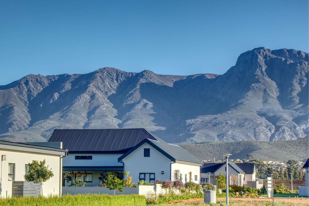 A scenic view of residential properties set against a dramatic mountain range backdrop, showcasing the estate's natural surroundings and well-maintained landscape.