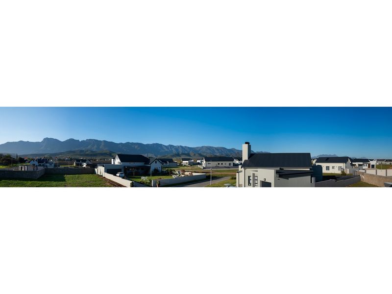 Panoramic view of a residential estate featuring modern homes set against a scenic mountain backdrop.