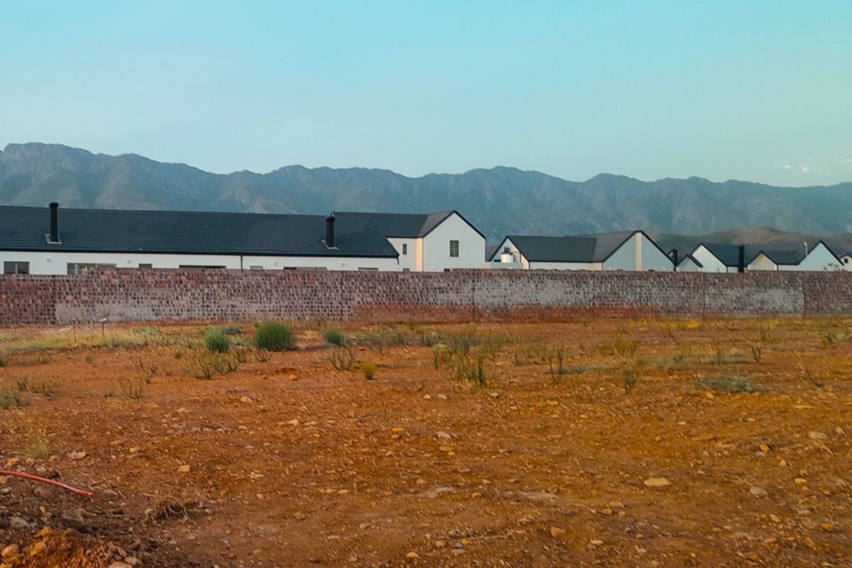 A vacant residential plot featuring a boundary wall with scenic mountain views in the background.