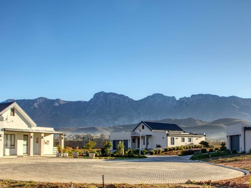 A well-maintained residential property featuring a paved driveway, modern architectural design, and scenic mountain views in a quiet estate setting.