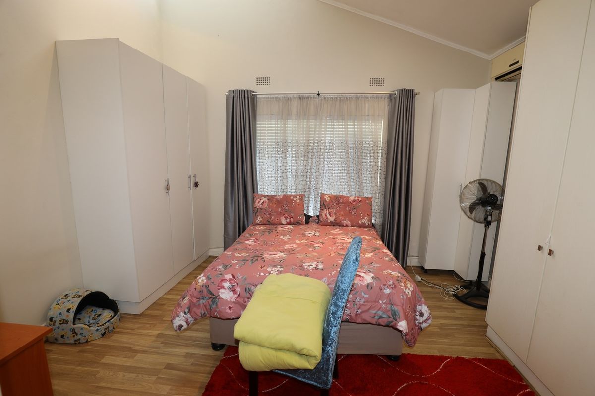 A bedroom featuring built-in wardrobes, laminate flooring, and a vaulted ceiling, providing a functional space with ample storage.