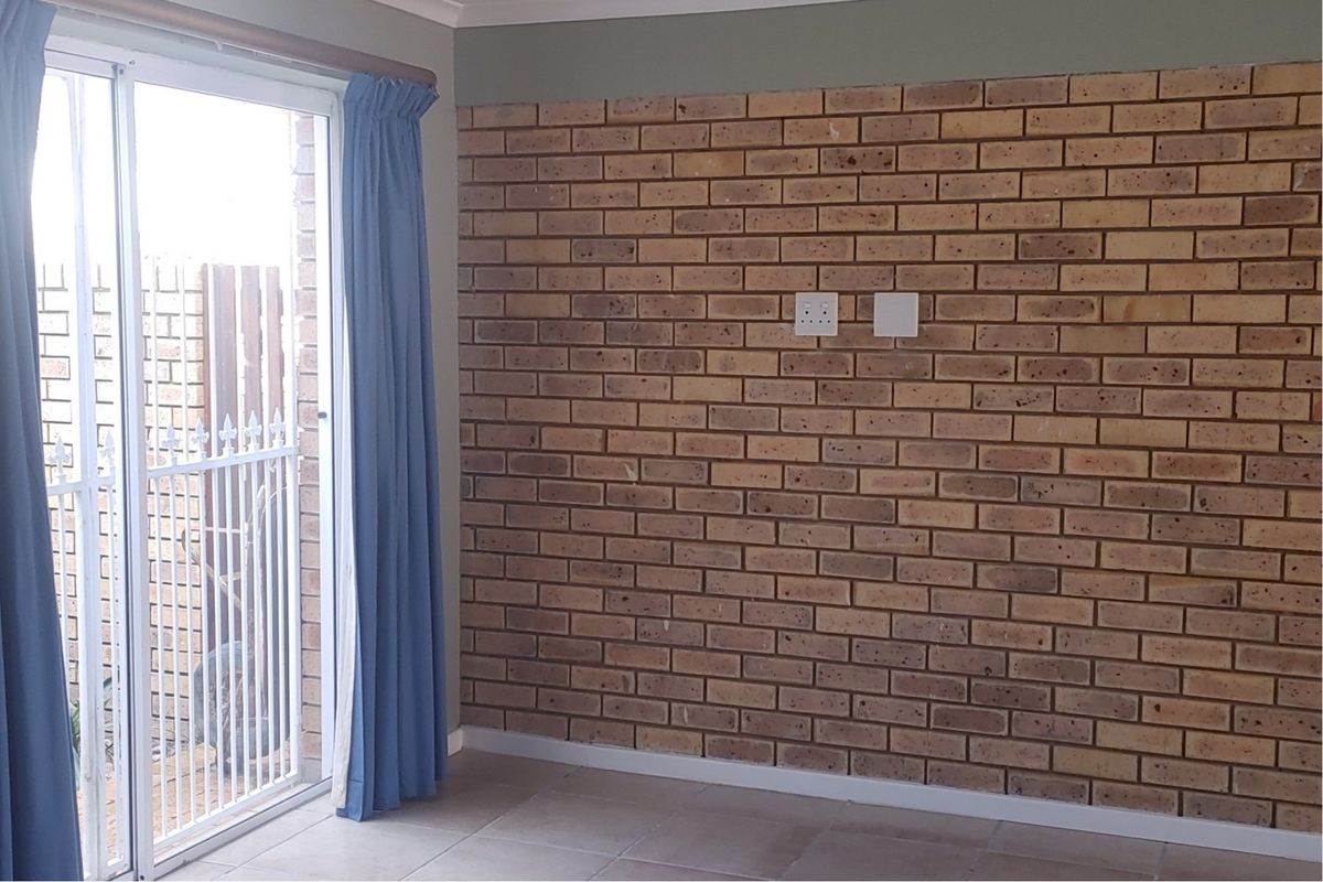 Living area featuring a prominent face-brick feature wall, tiled flooring, and sliding glass doors providing access to the outdoor space.