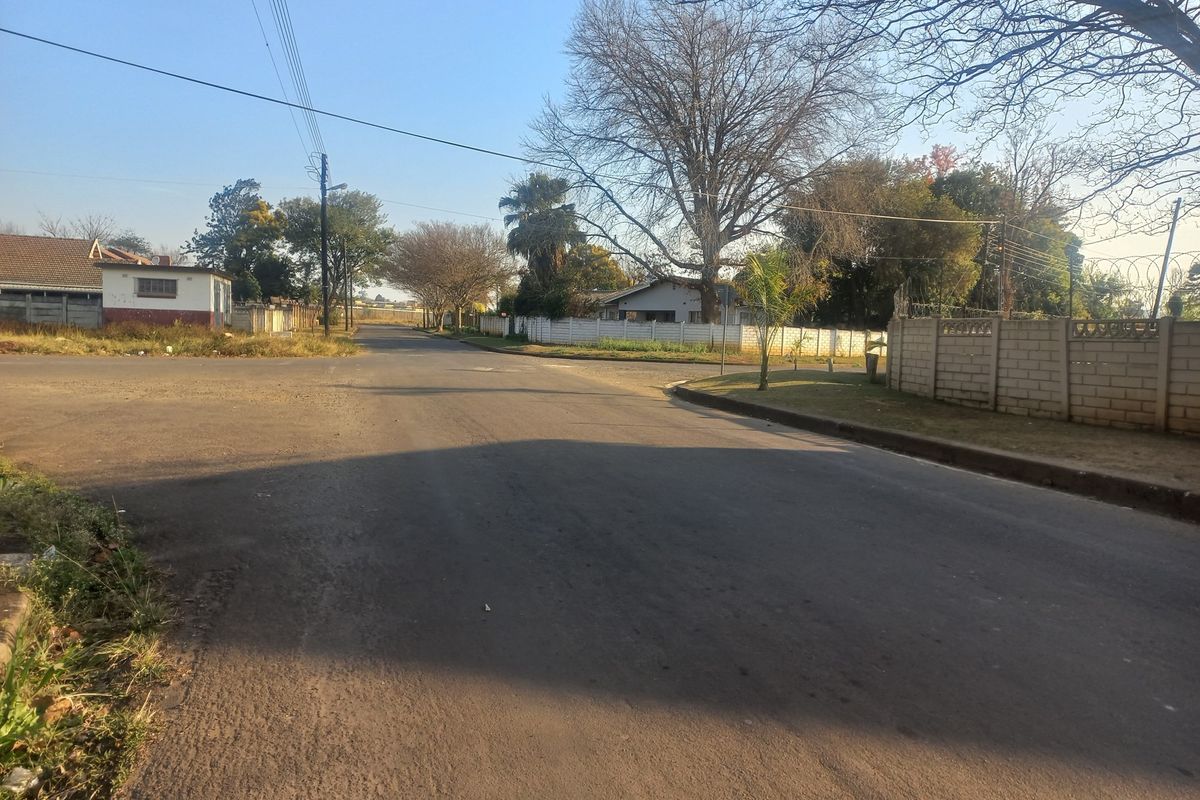 A view of the residential street approach showing the surrounding neighbourhood infrastructure and boundary walls.