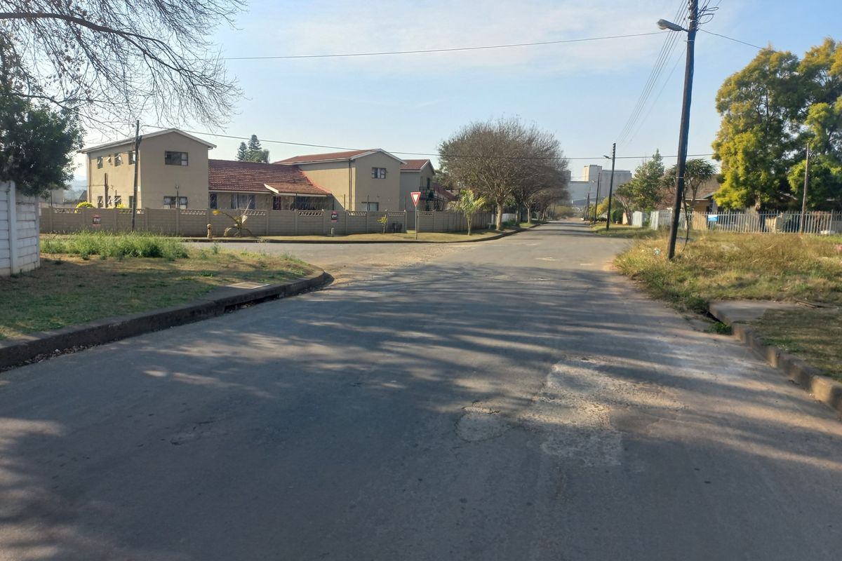 A view of the residential street approach showing the road surface, surrounding neighborhood properties, and perimeter boundary walls.