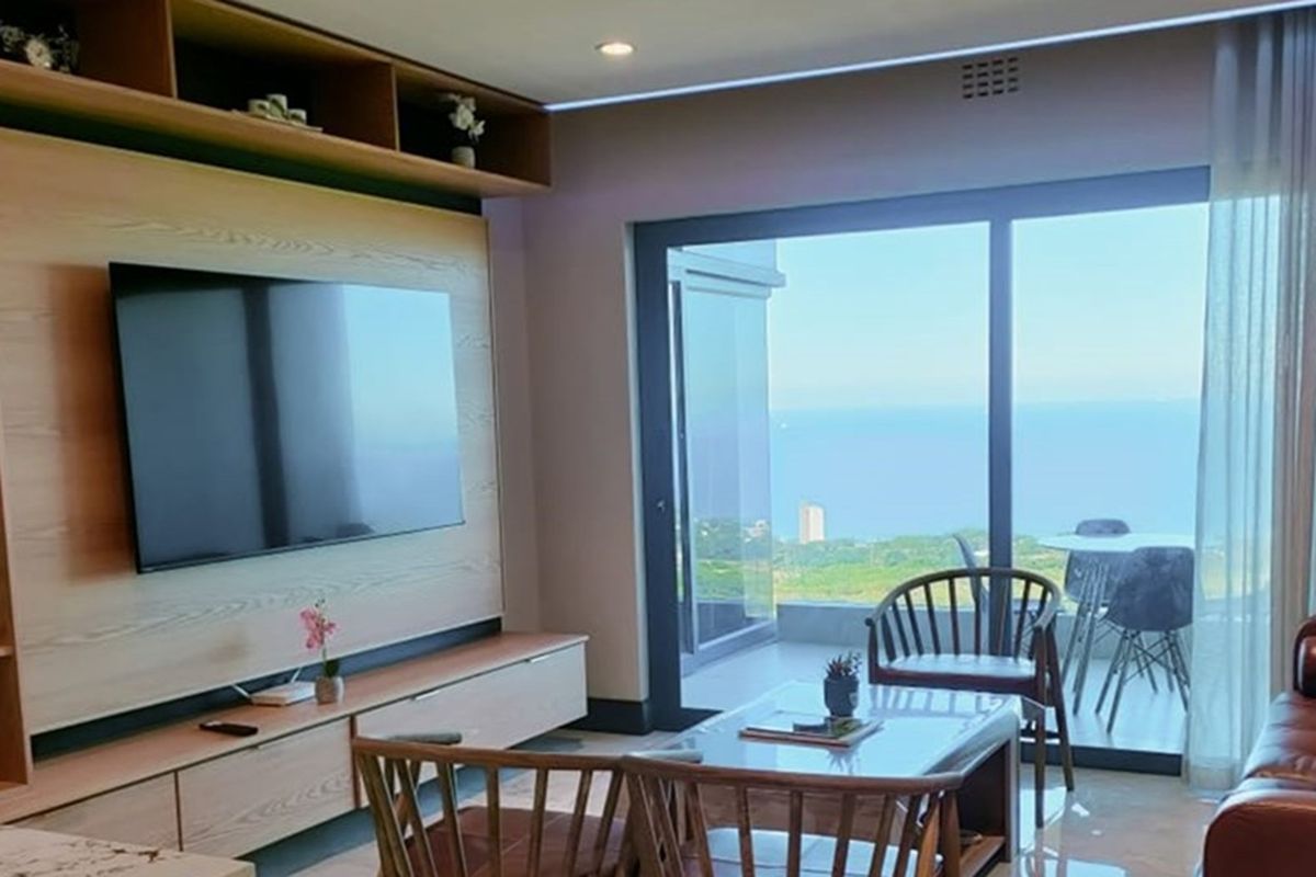 Modern living room featuring custom built-in cabinetry and large sliding glass doors that open to a balcony with expansive ocean views.