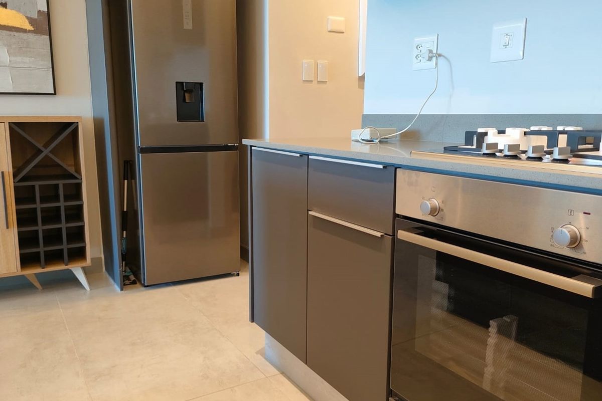 Modern kitchen featuring sleek grey cabinetry, stone countertops, a built-in oven, and a gas hob with tiled flooring.