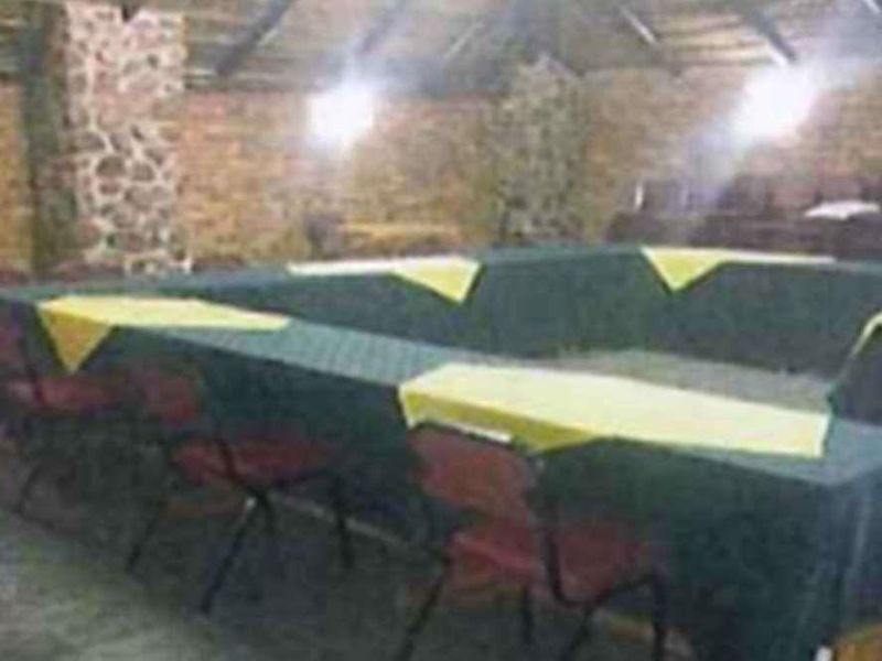 A rustic, open-plan entertainment or function area featuring exposed brick walls, stone pillars, and a high-pitched timber roof structure.