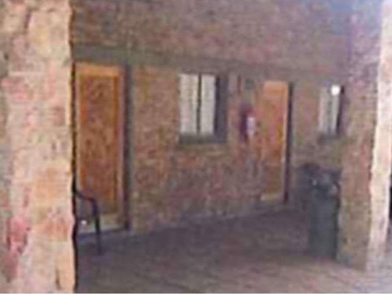 A covered patio area featuring rustic exposed brick walls, stone pillars, and multiple access points to the interior.