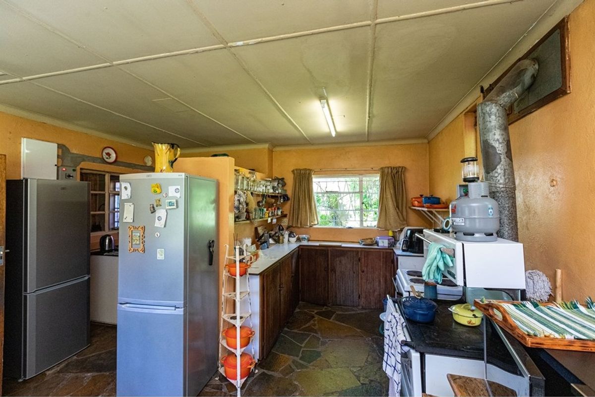 A dated kitchen featuring stone flooring, wooden cabinetry, and an exposed flue pipe, offering a rustic aesthetic with potential for modernization.