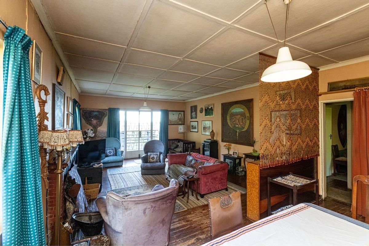 A spacious living area featuring original timber flooring, a decorative room divider, and access to an outdoor patio area.