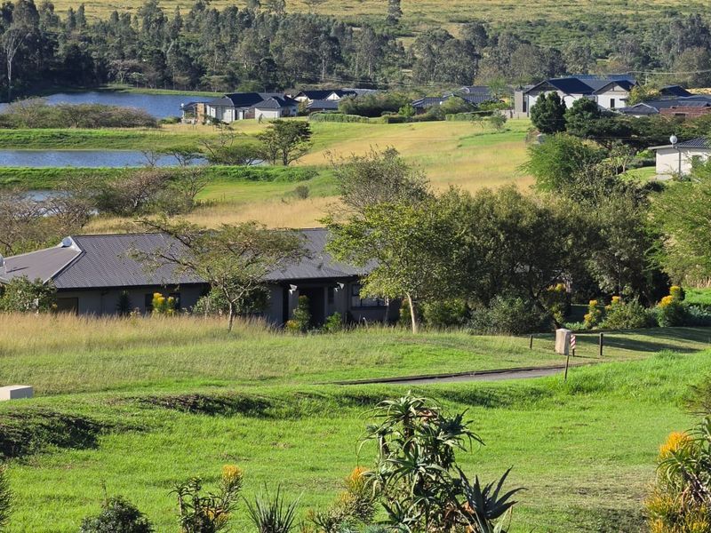 An elevated view of a residential estate featuring homes with metal roofs set within a scenic, landscaped natural environment with ponds.