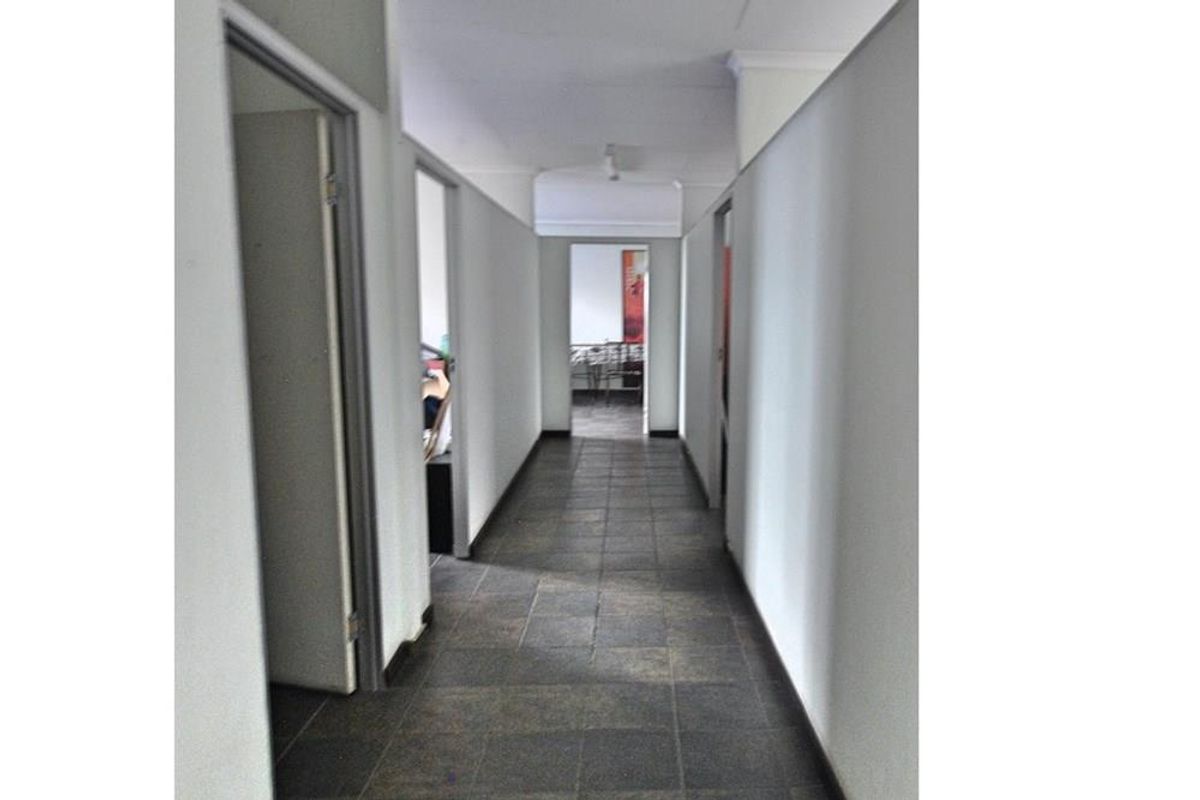 A functional commercial hallway featuring tiled flooring and multiple access points to adjacent office or utility spaces.