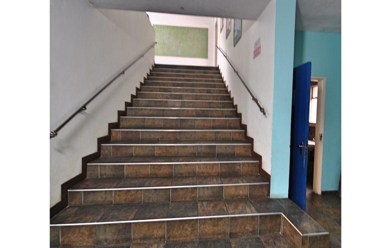 A functional interior staircase featuring tiled steps and metal handrails, providing access between levels in this commercial property.
