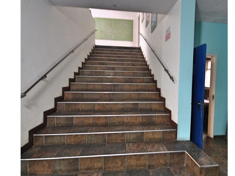 A functional interior staircase featuring tiled steps and metal handrails, providing access between levels in this commercial property.