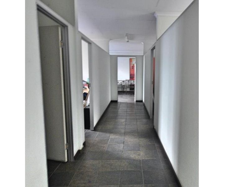 A functional commercial hallway featuring tiled flooring and multiple access points to adjacent office or utility spaces.