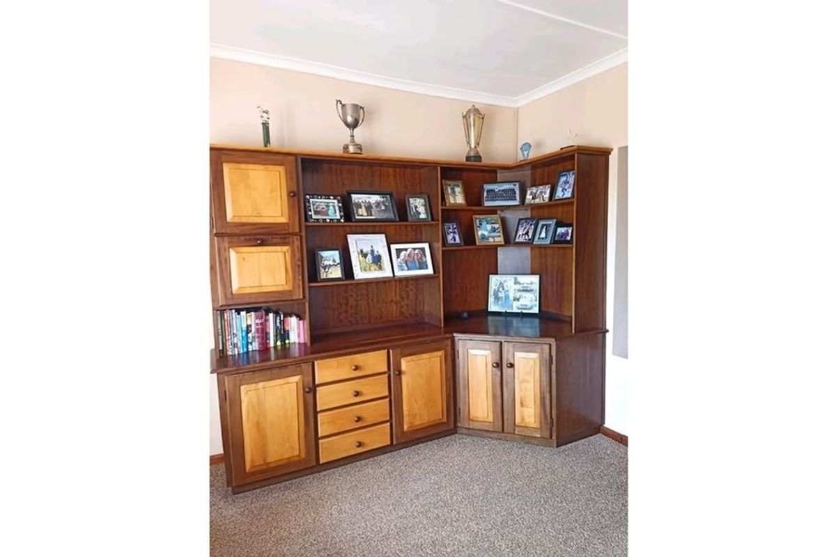 A corner study or display area featuring custom-built wooden cabinetry with integrated shelving and storage drawers.
