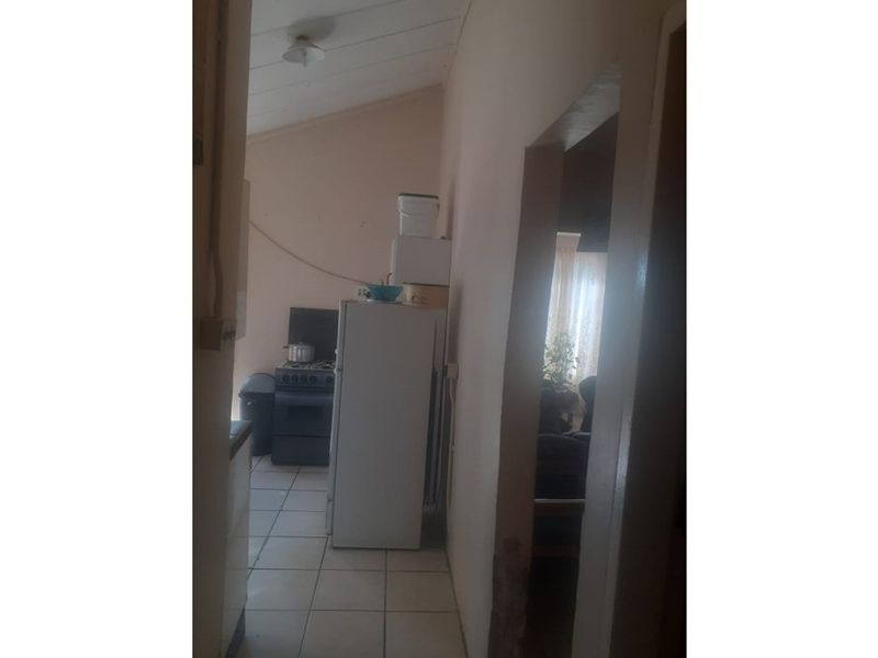 A small, dated kitchen area featuring tiled flooring and a sloped ceiling, requiring significant renovation and cosmetic updates to improve functionality and aesthetic appeal.
